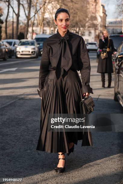 Bettina Looney wears black blouse, black maxi pleated skirt, black kitten heels shoes, Dior bag, outside Christian Dior, during the Haute Couture...