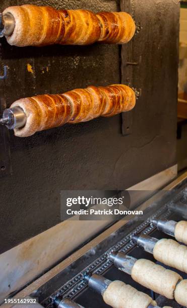 trdelniks cooking on rolling metal sticks, prague, czechia - trdelník stock pictures, royalty-free photos & images