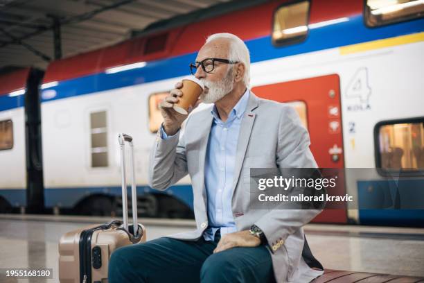 senior man sits at a train station and enjoys a coffee - serbia covid stock pictures, royalty-free photos & images