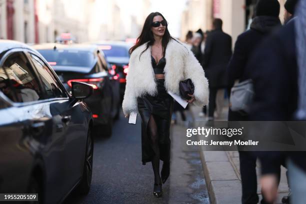 Fashion Week Guest seen wearing a white fur jacket, black short top, black leather skirt, black sunglasses and a leather handbag outside Christian...