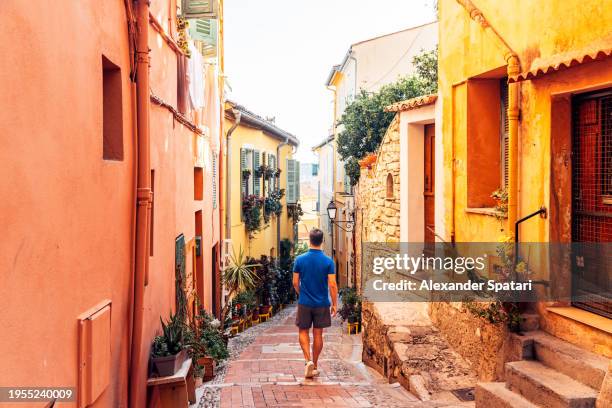 rear view of a man exploring narrow alleys of menton old town, french riviera, france - alpes maritimes - fotografias e filmes do acervo