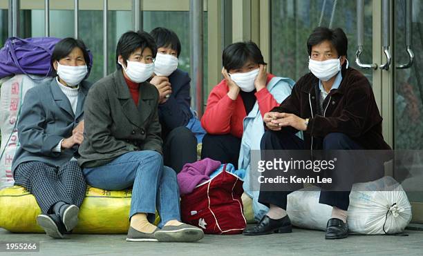 Chinese migrant workers wear surgical-type masks to protect themselves from the deadly SARS virus wait for their train at the station on April 28,...