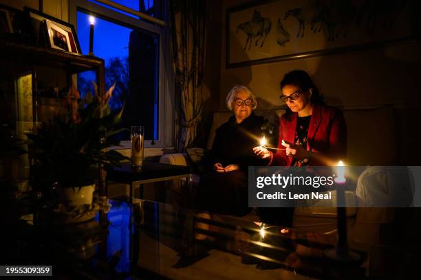 Joan Salter sits with Chief Executive of the Holocaust Memorial Day Trust Olivia Marks-Woldman as she lights a memorial candle at her home in north...