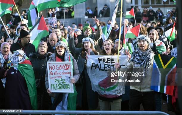 People, holding Palestinian flags and banners, gather outside the International Court of Justice during the session on the day the International...