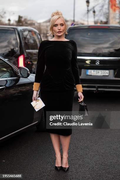 Guest wears black velvet midi dress, black Hermes bag, black heels, outside Schiaparelli, during the Haute Couture Spring/Summer 2024 as part of...