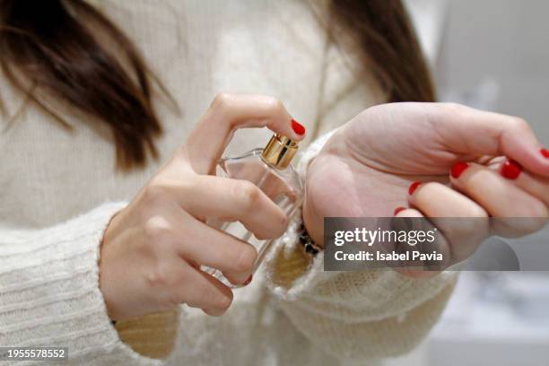 woman spraying perfume on wrist - perfumado imagens e fotografias de stock