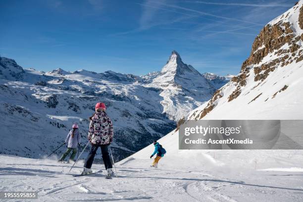 family of three skis down slope at ski resort - family skiing stock pictures, royalty-free photos & images