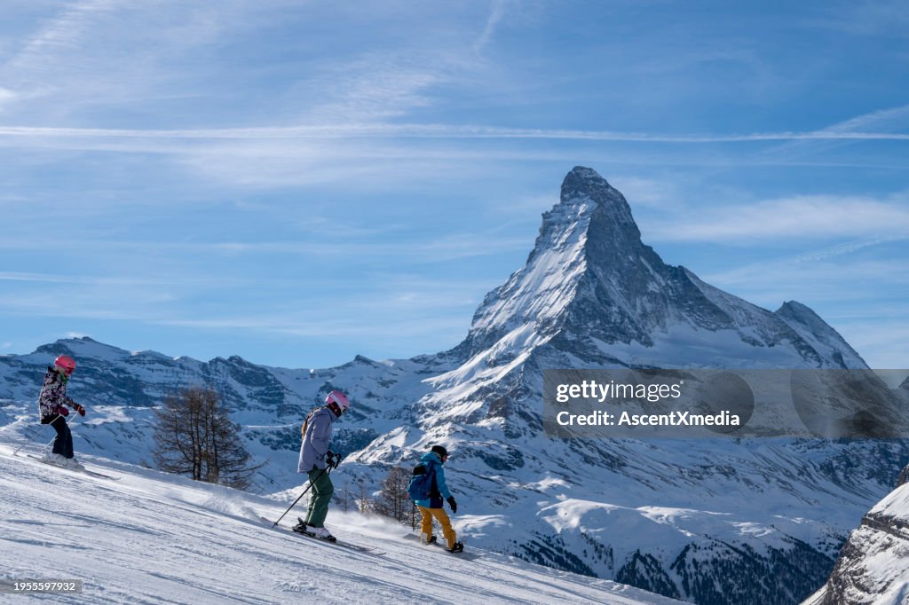 Family of three skis down slope at ski resort