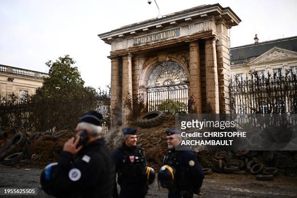 Police officers stand in front of the prefecture after farmers of the CR47 union dumped slurry, manure, tyres and debris at the entrance of the...