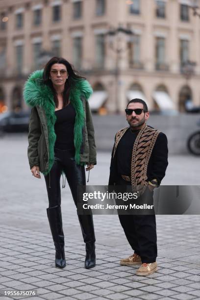 Marina Vernicos seen wearing brown aviator sunglasses, silver diamond earrings, silver necklace, black one shoulder top, khaki green fur parka...