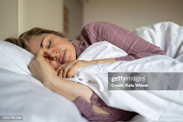 mature woman suffering from menopause symptoms while lying in bed - slapen stockfoto's en -beelden