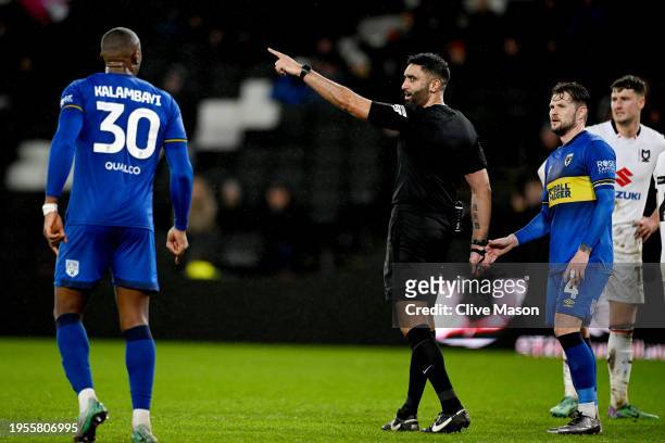 Referee Sunny Sukhvir Gill gestures for Paul Kalambayi of AFC Wimbledon to leave the pitch after showing him a red card during the Sky Bet League Two...