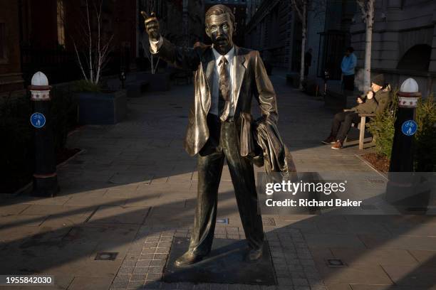 City worker smokes on a bench near the sculpture by J. Seward Johnson Jr, entitled 'Taxi' on John Carpenter Street in the City of London, the...