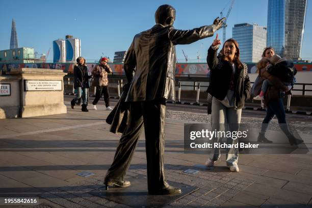 Visitor to London copies finger-pointing of the sculpture by J. Seward Johnson Jr, entitled 'Taxi' on John Carpenter Street in the City of London,...