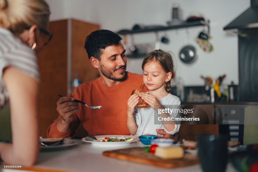 A Happy Beautiful Cute Girl Having Breakfast With Her Family At Home