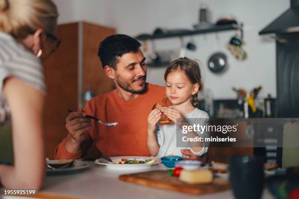 a happy beautiful cute girl having breakfast with her family at home - sandwich bildbanksfoton och bilder