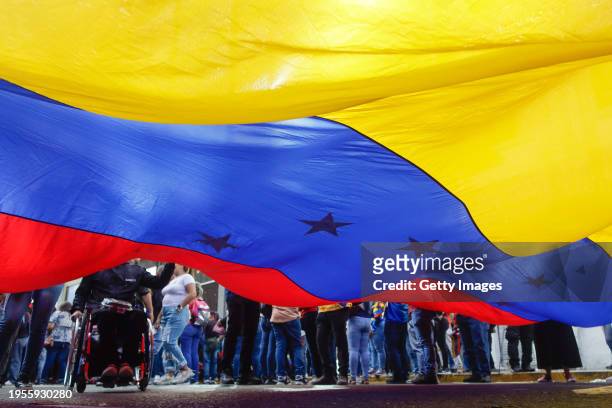 Supporters of President of Venezuela Nicolas Maduro hold and wave a giant Venezuelan flag during a march for the 65th anniversary of the overthrow of...