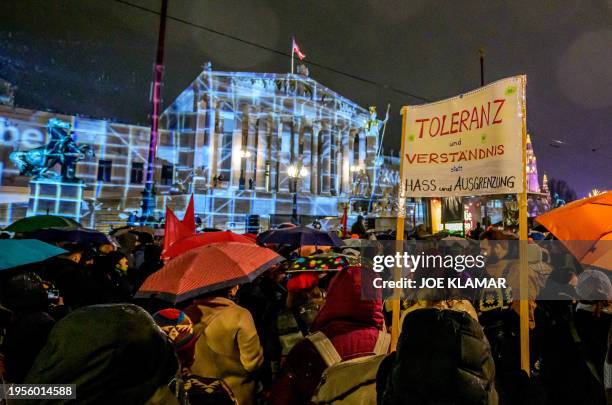 People take part in a rally under the motto "Defend Democracy" against right-wing extremism, racism and anti-Semitism as rain falls in front of the...