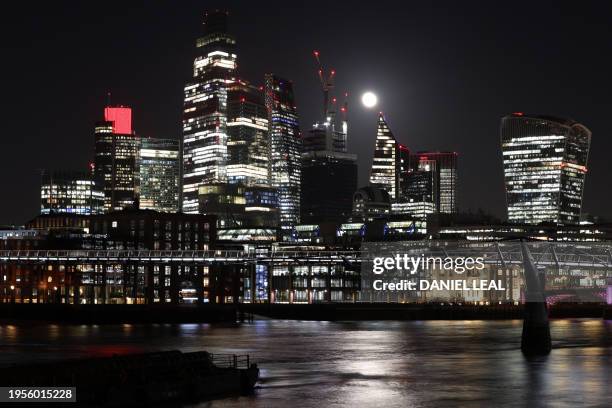 Waning Gibbous moon is seen behind office buildings in the City of London, viewed from the south side of the River Thames in London on January 26,...