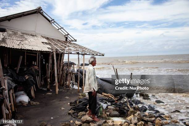 Carmat is staring out to sea near the remains of his house, which was destroyed by high waves in Cemarajaya Village, Karawang Regency, West Java...