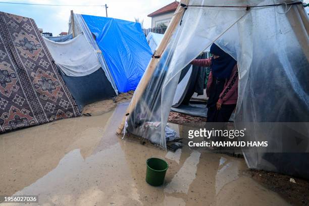 Displaced Palestinian woman stands at the entrance of a tent flooded by heavy rain, at a makeshift camp set up by people who fled the ongoing battles...