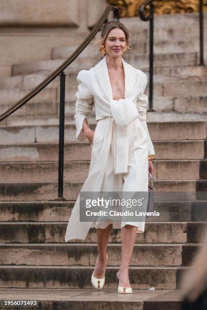 Natalia Vodianova wears cream blouse, cream cropped pants, silver Schiaparelli bag, gold earrings, cream Schiaparelli heels, outside Schiaparelli,...