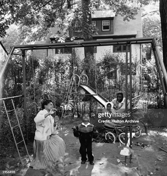 American baseball player Jackie Robinson and his wife Rachel play with son Jackie Jr. And daughter Sharon in the backyard of their home in Stamford,...