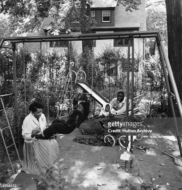 American baseball player Jackie Robinson and his wife Rachel play with son Jackie Jr. And daughter Sharon in the backyard of their home in Stamford,...