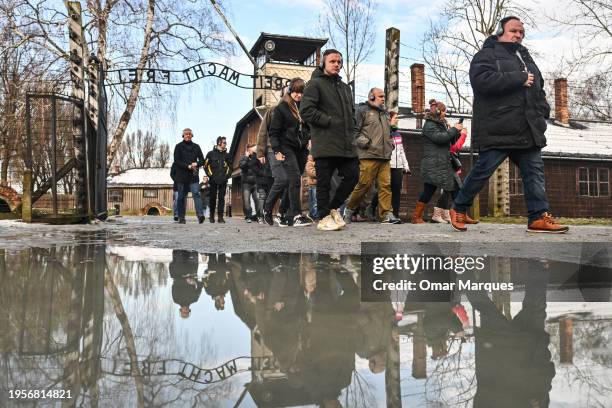Visitors walk past the former Auschwitz concentration camp that reads 'Arbeit Macht Frei' on January 23, 2024 in Oswiecim, Poland. Among the...