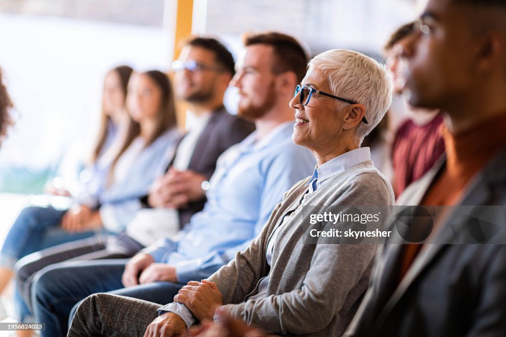 Happy senior businesswoman attending a seminar in board room.