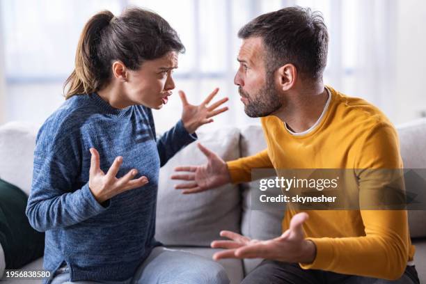 mid adult couple arguing on sofa at home. - in the dog house stock pictures, royalty-free photos & images