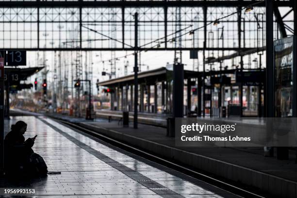 Woman sits on the ground with her luggage on an empty railroad track in the main train station during a nationwide strike by the GDL union of...