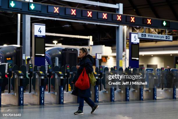 Woman walks past barriers at an empty Queen Street station as all trains across Scotland's rail network have been cancelled due to Storm Jocelyn on...