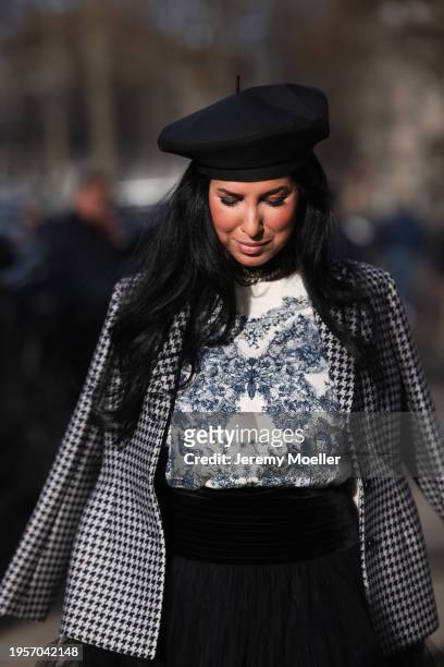 Tina Odjaghian seen wearing black beret hat, silver earrings, silver necklace, white / navy blue butterfly print pattern sweater, white / black...