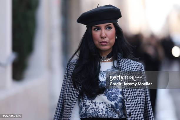Tina Odjaghian seen wearing black beret hat, silver earrings, silver necklace, white / navy blue butterfly print pattern sweater, white / black...