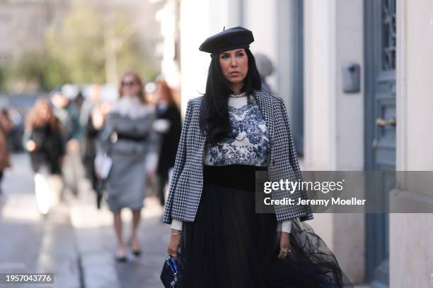 Tina Odjaghian seen wearing black beret hat, silver earrings, silver necklace, white / navy blue butterfly print pattern sweater, white / black...