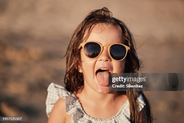 little girl with her tongue out on the beach - mensentong stockfoto's en -beelden