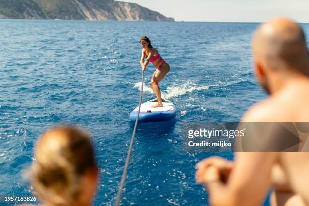 woman surfing on a paddleboard - levkas stock pictures, royalty-free photos & images