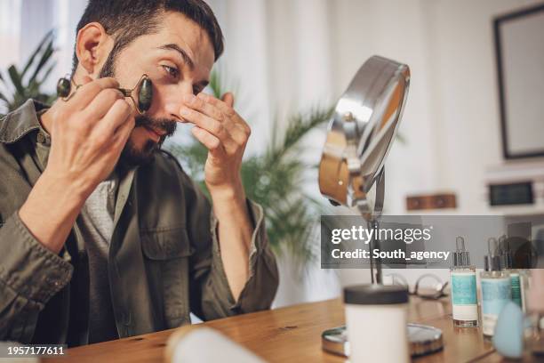 man using jade roller for massaging his face for his facial treatment at home - roll on bildbanksfoton och bilder