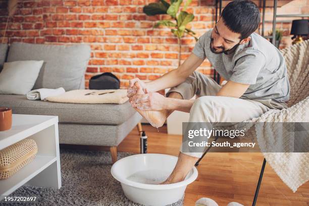 man relaxing at home having a foot bath - man wash body stock pictures, royalty-free photos & images