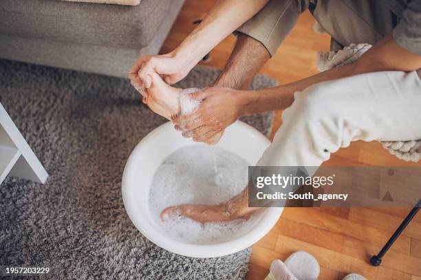 uomo che si rilassa a casa con un pediluvio - pedicure foto e immagini stock