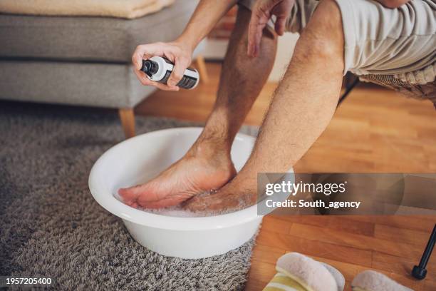 man relaxing at home having a foot bath - man wash body stock pictures, royalty-free photos & images