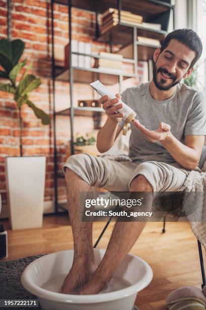 hombre tomando un baño de pies y aplicando loción corporal - crema corporal fotografías e imágenes de stock