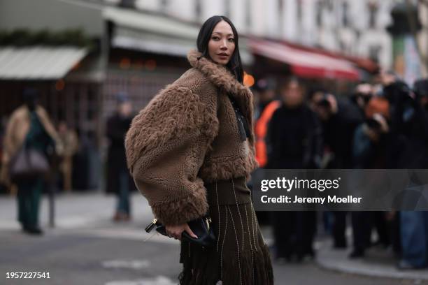 Soo Joo Park is seen wearing an oversized brown fur jacket with different lengths of fur, a midi skirt in olive green with long fringes, high black...