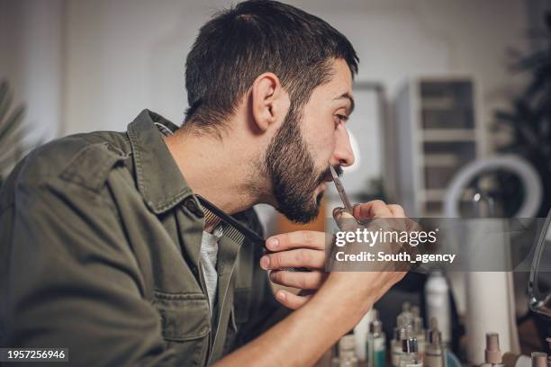 man grooming his beard at home - tweezing eyebrows stock pictures, royalty-free photos & images