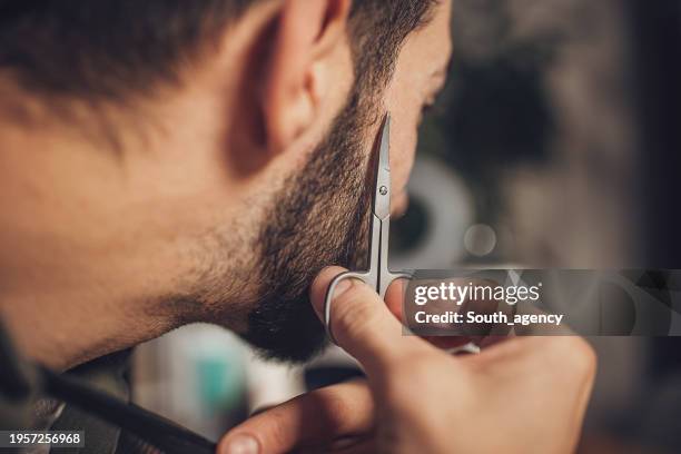 man grooming his beard at home - beard trimming stock pictures, royalty-free photos & images