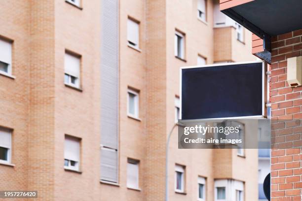 a very large residential building with many windows, there is an empty sign on the corner of another building. - placa de manifestação imagens e fotografias de stock