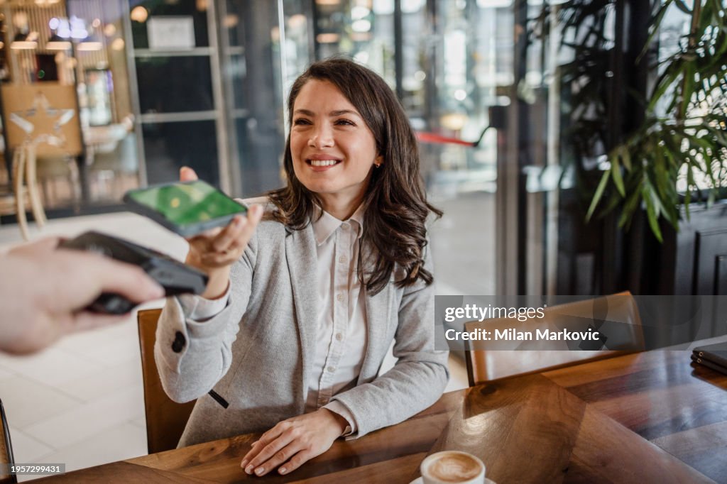 A guest in a restaurant pays contactless using a mobile phone