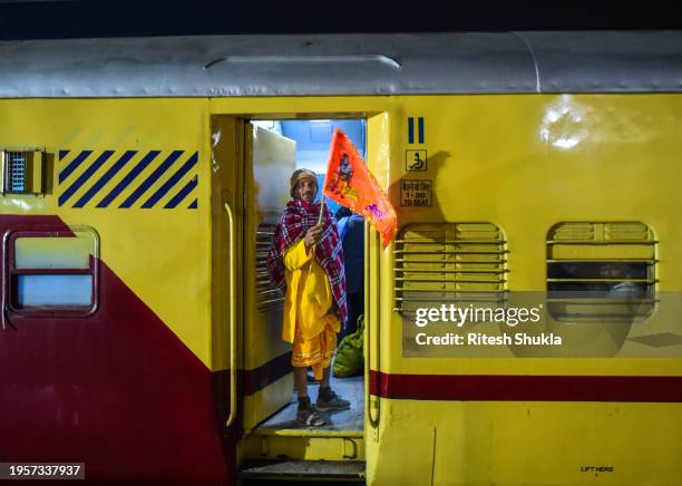 Devotee holds a saffron flag at the coach door while waiting for his train to depart at Ayodhya railway station one day after consecration ceremony...