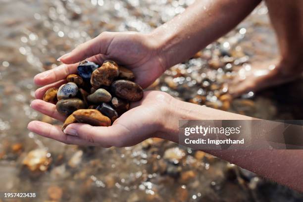 closeup of teenage girl playing with beautiful stones at a jurrasic coast beach, dorset, united kingdom - handful stock pictures, royalty-free photos & images